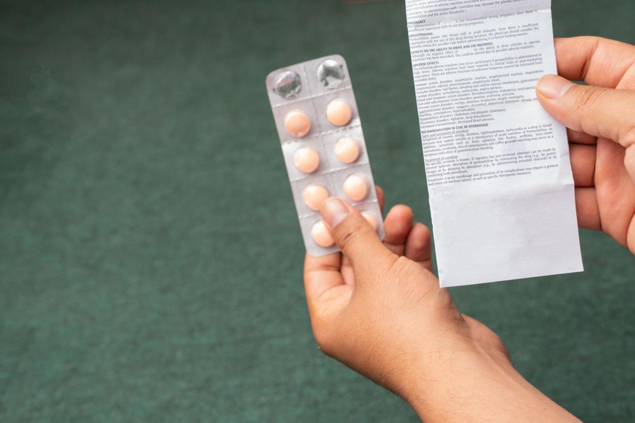 Close up of a hand holding a prescription, prescription and a strip, medicine blister pack, vitamins, reading prescription