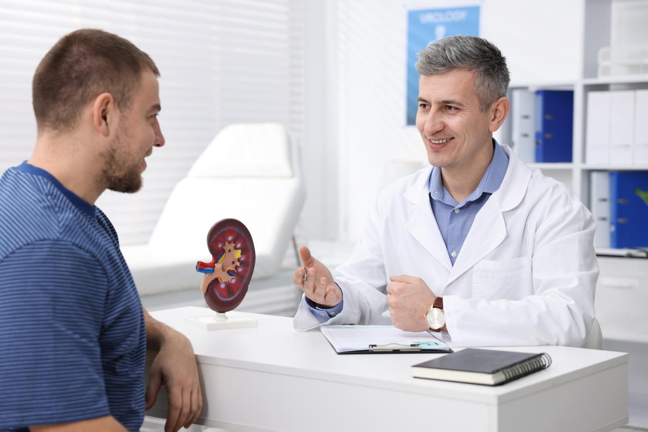 Man having appointment with smiling urologist at white desk in clinic